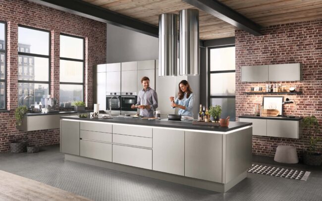 Modern kitchen with brushed steel finish from the Inox range by German Kitchen Warehouse, showcasing an industrial chic look with integrated shelving and stainless steel elements